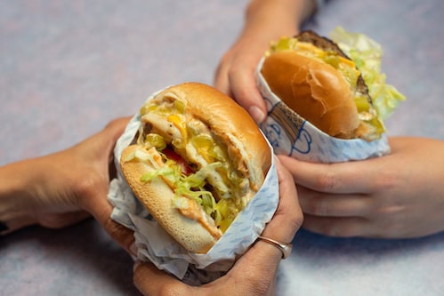 Two Fosters Freeze hamburgers held together by two people's hands