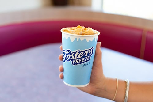 Woman holding a foster's Freeze custard shake in front of a booth