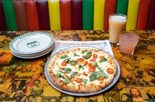 Barney's Beanery pizza with cocktail on a table with booth