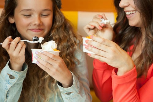 Mother and daughter enjoying two cups of frozen yogurt