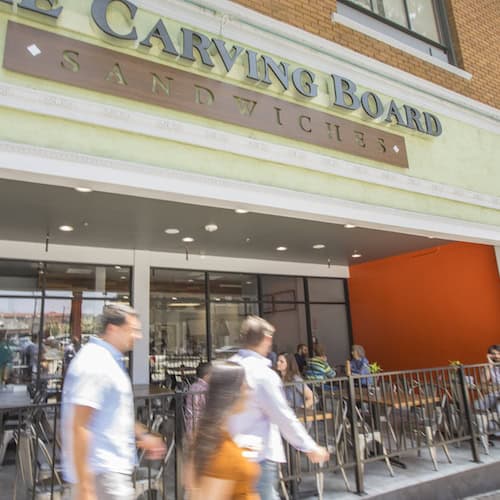 Carving Board sign outside front entrance with three people walking by