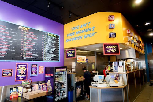 Ike's Love and Sandwiches deli counter with yellow and purple walls and menu