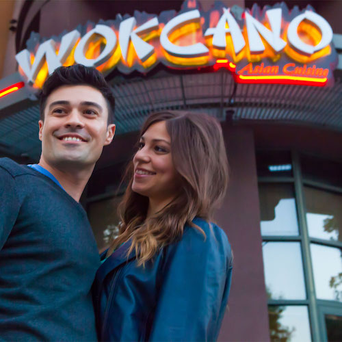 Couple in blue shirts standing in front of Wokcano sign