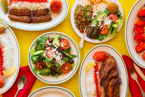 Many dishes of Mediterranean food on a yellow table