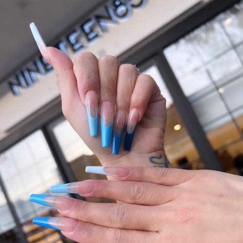 Manicure with blue tips and Nineteen85 Sign in background