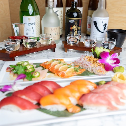 Sushi platter with sake bottles and cups in background