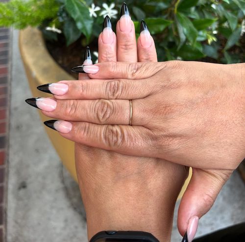 Two hands showing manicure featuring white nail and black tips