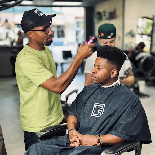 Purpose LA Barbershop barber works on a man's hair while he is in the chair