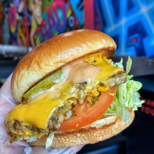 Smashed burger being held against the mural