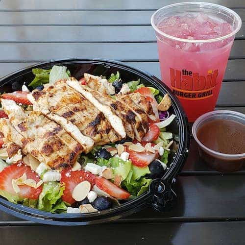 Chicken salad in black plastic bowl and red drink