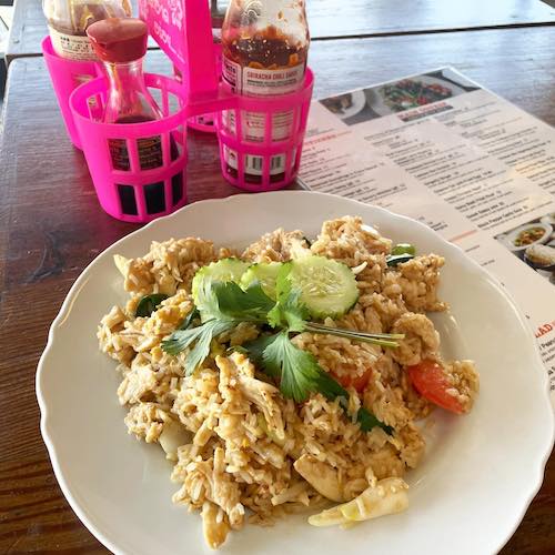 Thai fried rice on a table with menu and pink