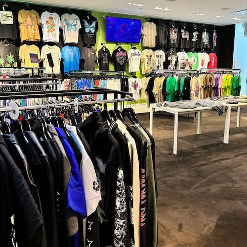 Inside of Gear Locker store with a row of hanged clothes in front of a wall of t-shirts.