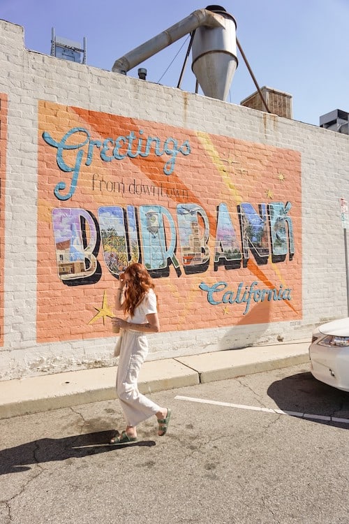 Woman standing in front of the postcard mural