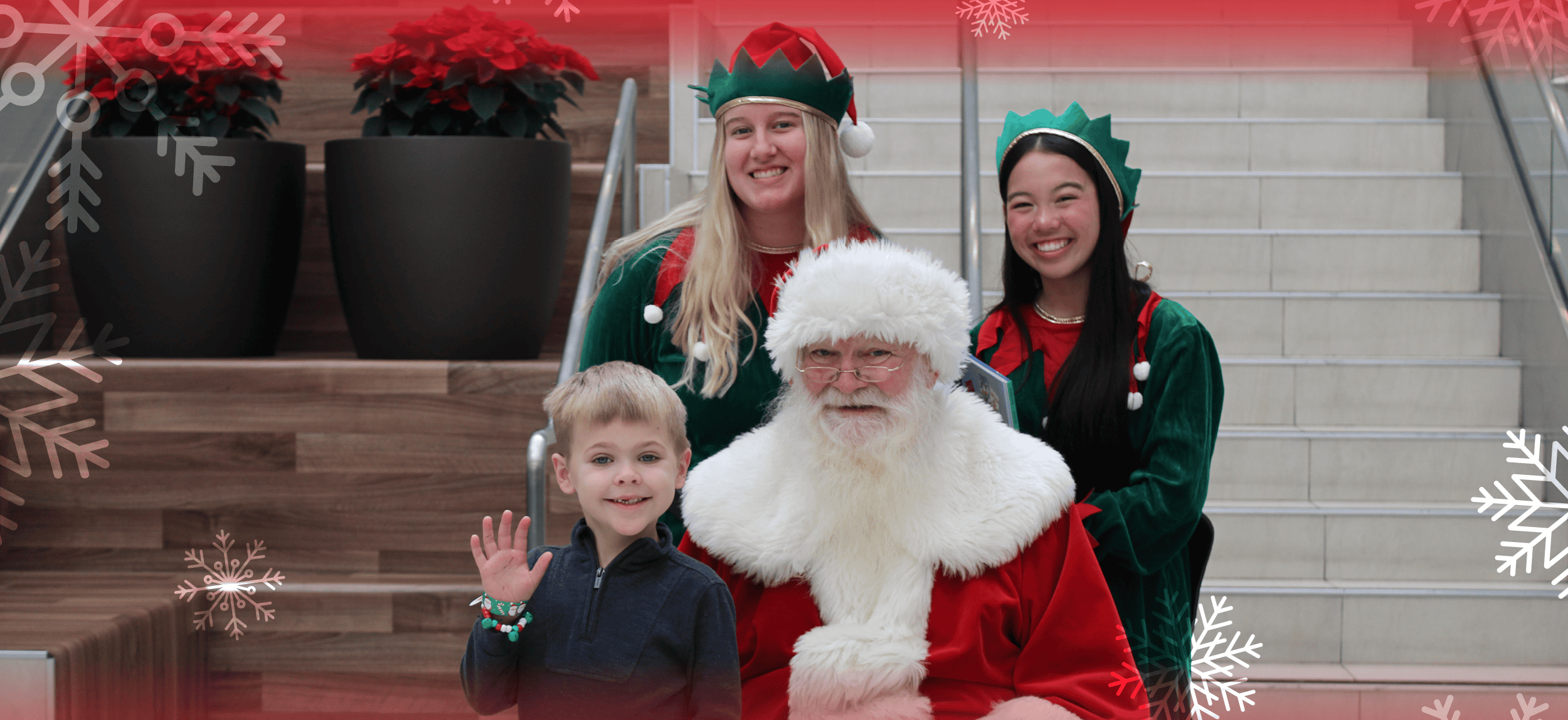 Santa and his two elves pos with a blond haired boy