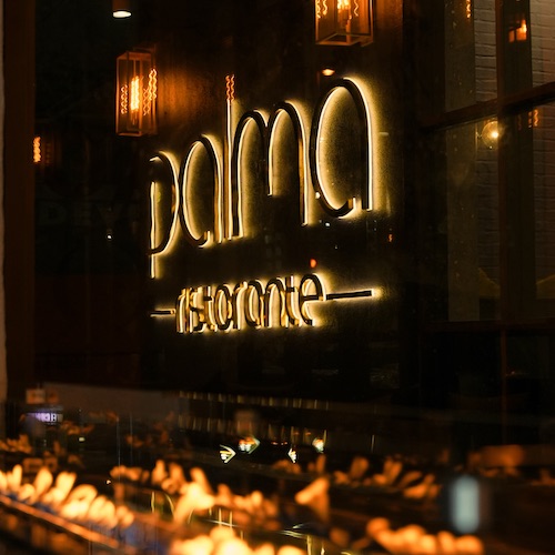 Palma Ristorante sign illuminated in yellow above flames