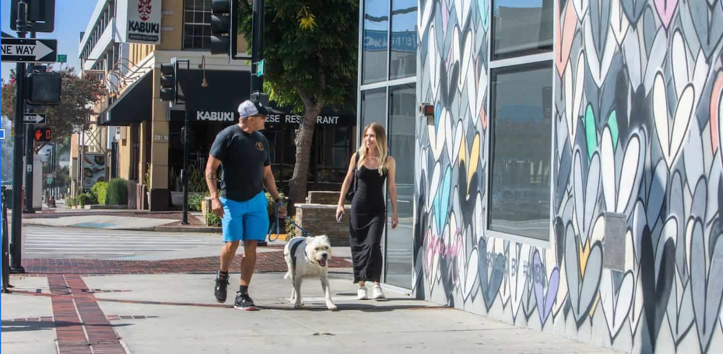 Couple walking their dog past a heart-covered mural in Downtown Burbank.