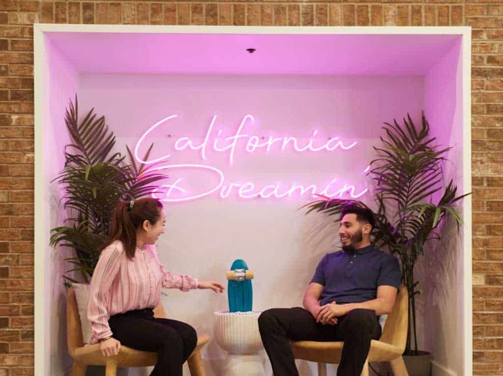 Romantic couple at a Burbank Valentine's Day restaurant with a pink California Dreamin' neon sign.